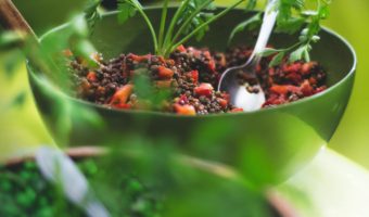 close-up of bowl of quinoa and lentil salad in field of greens