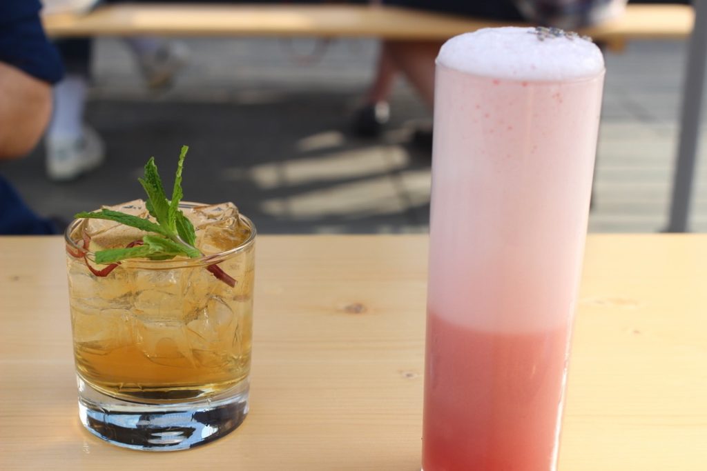 Cocktails with mint leaves and scotch and sweet fruit egg white froth on wooden picnic table