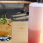 Cocktails with mint leaves and scotch and sweet fruit egg white froth on wooden picnic table