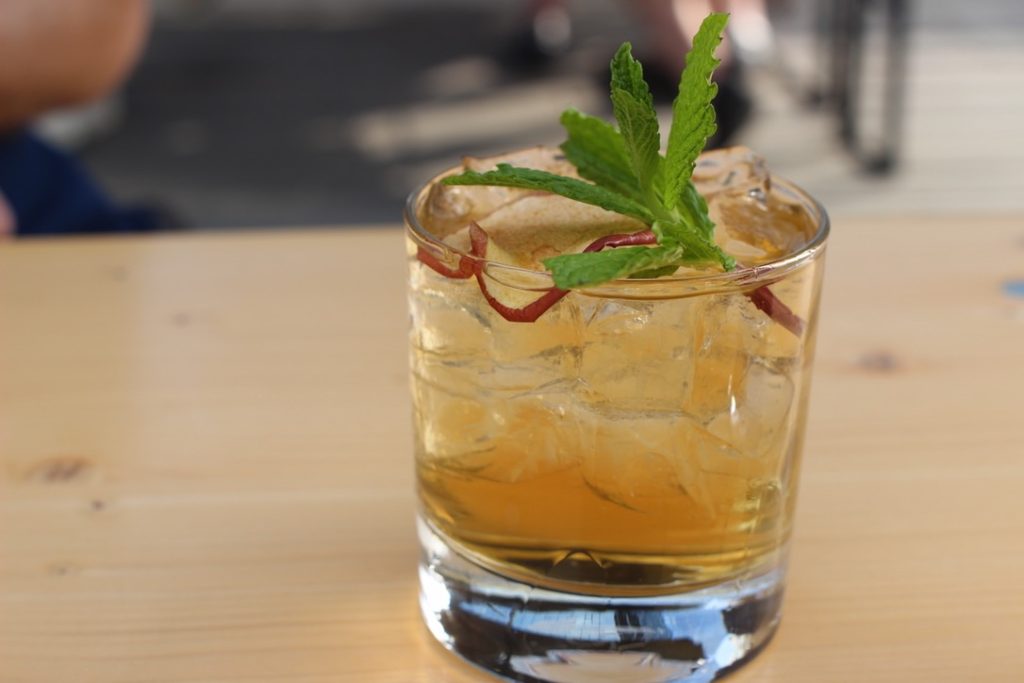 Cocktail with mint leaves and scotch on wooden picnic table